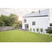 Pohľad na moderný dom so záhradou, trávnikom a dreveným plotom