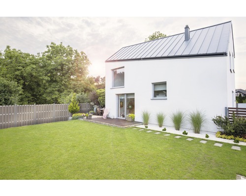 Pohľad na moderný dom so záhradou, trávnikom a dreveným plotom