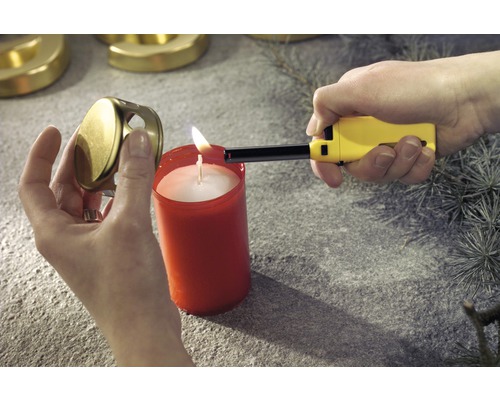 Osoba zapaľuje sviečku zapaľovačom. Vedľa sviečky leží viečko na sviečku.