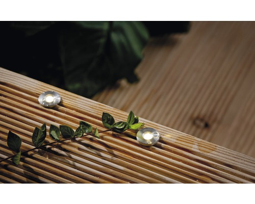 Dve zemné svietidlá sú zapustené v drevenej terasovej podlahe a svietia.