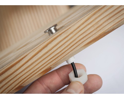 Detailný pohľad na kus dreva s priechodkou kábla a skrutkou