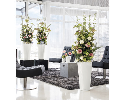 Svetlý interiér s kvetinovou výzdobou vo vysokých kvetináčoch, kreslách a koberci