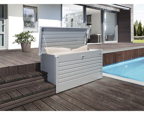 Otvorený kovový úložný box s vankúšmi na drevenej terase vedľa bazéna