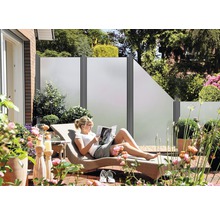 Terasa s prvkami na ochranu súkromia, záhradným nábytkom a ženou na lehátku