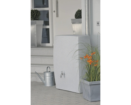 Nádrž na vodu s kohútikom, krhlou a rastlinami pred domom