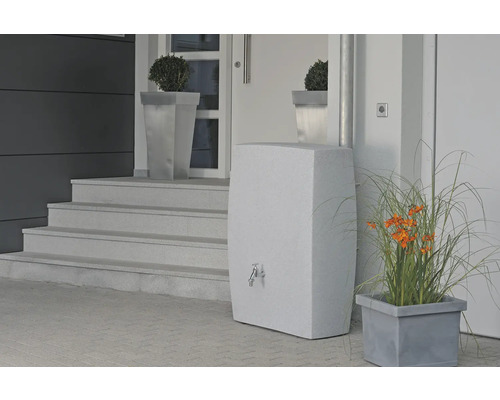 Snímka fasády domu so štýlovým zásobníkom vody s kohútikom, po stranách sú kvetináče s rastlinami