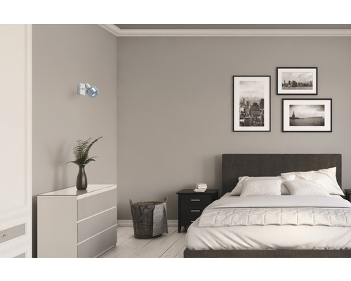 Spálňa s posteľou, komodou, nočným stolíkom, nástennou lampou a zarámovanými obrazmi