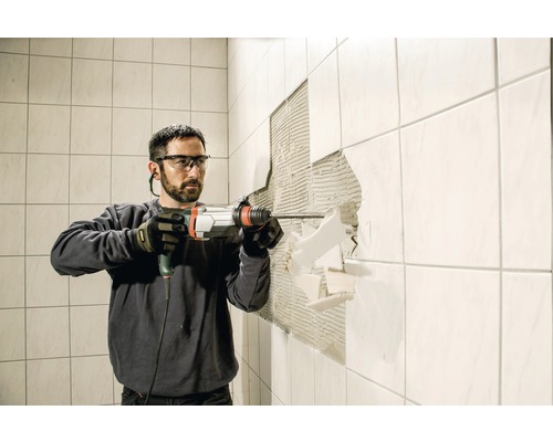 Muž odstraňuje dlaždice pomocou vŕtacieho kladiva