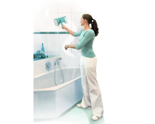 Žena čistí obkladačky v kúpeľni stierkou na okná vedľa vane