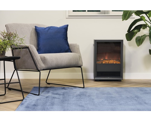 Obývacia izba s kreslom, ozdobným vankúšom, príručným stolíkom, izbovou rastlinou, kobercom a elektrickým krbom