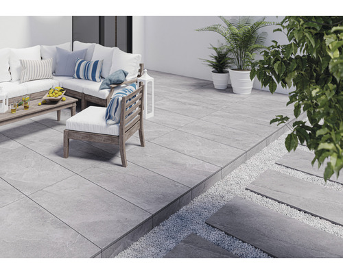 Terasa so sivými dlaždicami, záhradným nábytkom a rastlinami.