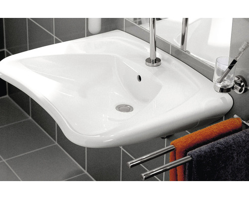 Keramické umývadlo v kúpeľni s uterákmi, pohárom na zubné kefky a batériou.