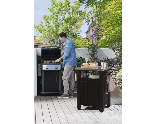 Scéna s mužom pri grile a grilovacím stolom v záhrade