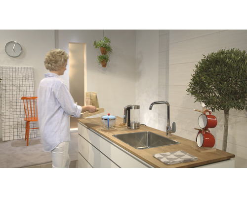 Moderná kuchyňa s drezom, batériou a kuchynským náčiním na drevenej doske