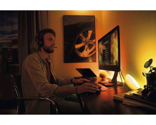 Scéna muža so slúchadlami pred počítačom, osvetleného dvoma stolnými lampami