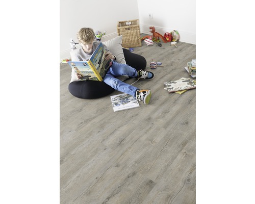 Chlapec číta knihu na svetlej drevenej podlahe v detskej izbe.