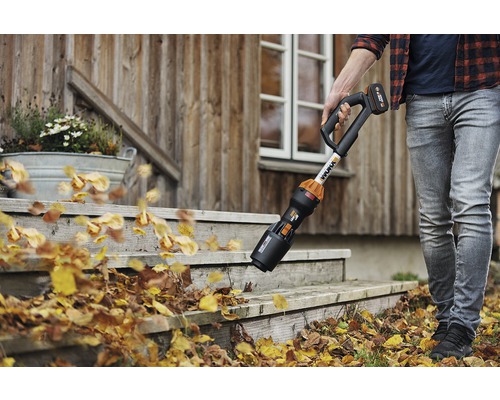 Osoba odstraňuje lístie z schodov pred domom pomocou akumulátorového fúkača lístia.
