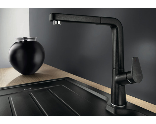 Čierna kuchynská batéria s výsuvnou sprchou vedľa drezu a dekorácie