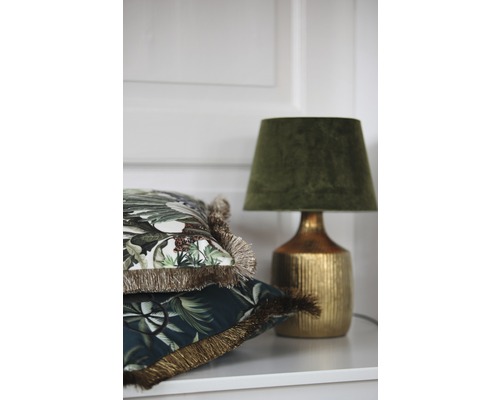 Ozdobné vankúše s strapcami a stolná lampa na polici.