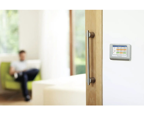 Scéna obývacieho priestoru s digitálnym termostatom na stene.