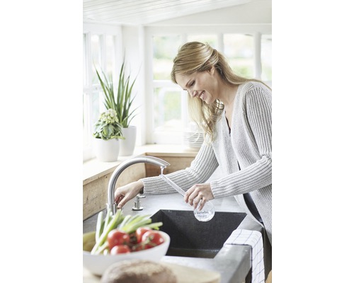 Žena umýva zeleninu v kuchynskom dreze s batériou.