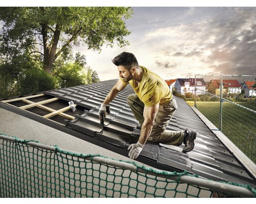 Remeselník upevňuje strešné tašky na streche.