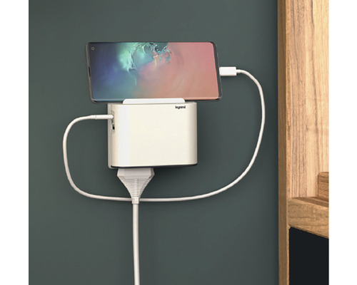 Mobilný telefón pripojený k bielej nabíjacej stanici na stene