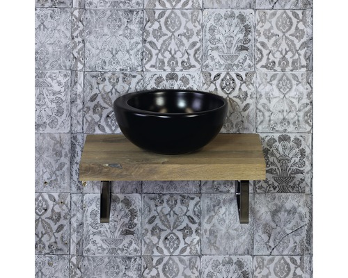 Čierne umývadlo na doske z dreva s obkladmi na stene v pozadí