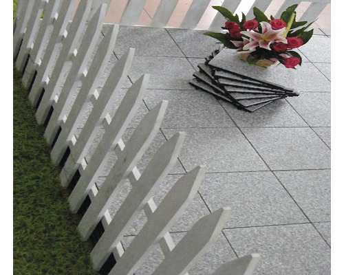 Scéna so sivými terasovými dlaždicami, bielym plotom a kyticou kvetov