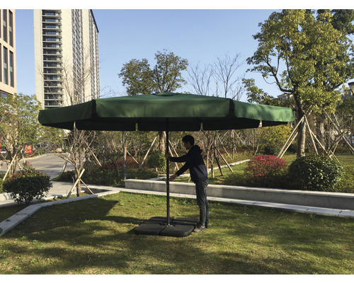 Štvorcový záhradný slnečník s osobou upravujúcou veľkosť v záhrade.