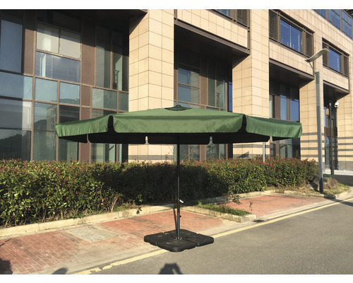 Záhradný slnečník s krížovou základňou na terase pred budovou.