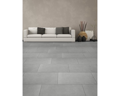 Svetlá obývacia izba s dlaždicami, pohovkou a dekoráciami.