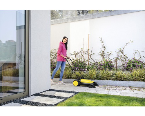 Žena používa zametací stroj na čistenie terasy