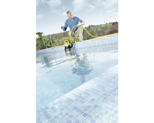 Muž spúšťa ponorné čerpadlo s hadicou do bazéna