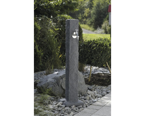 Záhradná scéna s kamenným vodným stĺpikom s kovovým kohútikom.