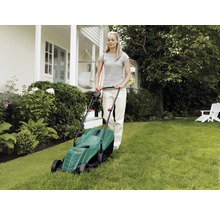 Žena obsluhuje kosačku na trávu v záhrade.