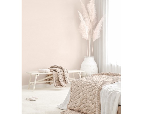 Svetlá spálňa s posteľou, lavicou, prikrývkami, vankúšmi a pampovou trávou vo váze