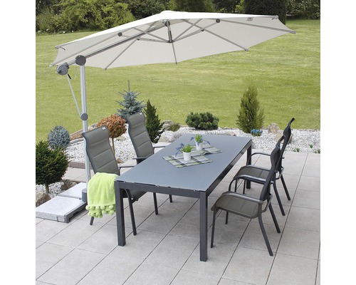 Záhradná scéna so slnečníkom, stolom a stoličkami na terase.