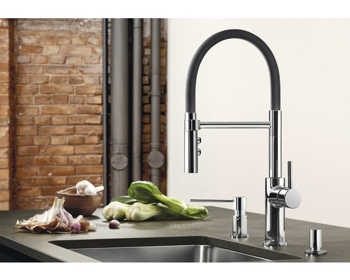 Kuchynská scéna s drezovou batériou, dávkovačom mydla a zeleninou na kuchynskej linke.