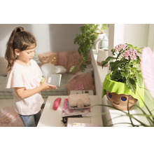 Dievča s poznámkovým blokom vedľa kvetináča s dizajnom tváre v detskej izbe.