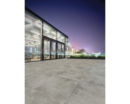 Pokládka vonkajších dlaždíc pred modernou budovou v noci.