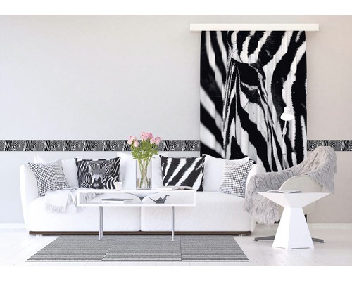 Obývacia izba s pohovkou, vankúšmi, bordúrou na stenu a posuvným panelom so zebra motívom.