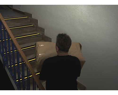 Muž nesie balík po schodoch s protišmykovými pásmi