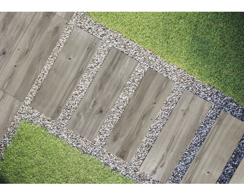 Záhradná scéna s chodníkovými dlaždicami s dreveným vzhľadom, lemovaná štrkom a trávnikom