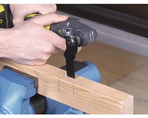 Multifunkčný nástroj reže kus dreva upnutý v zveráku.