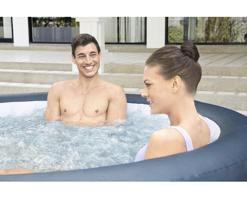 Dvaja ľudia relaxujú vo vonkajšej nafukovacej vírivke.