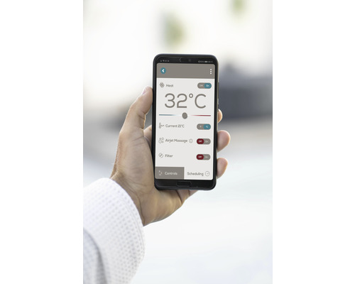 V ruke je držaný smartfón s aplikáciou na ovládanie kúrenia, masáže a funkcií filtra.