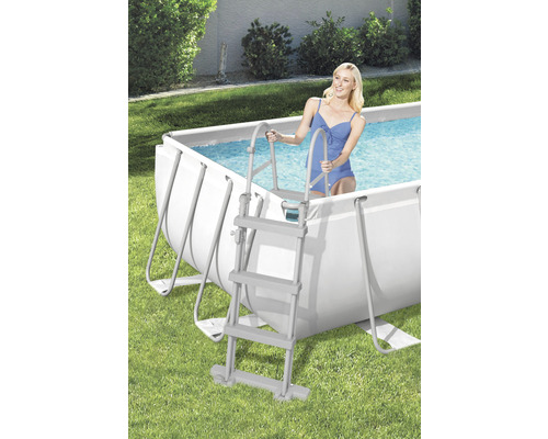 Scéna s oceľovým rámovým bazénom a ženou vstupujúcou do vody po bazénovom rebríku