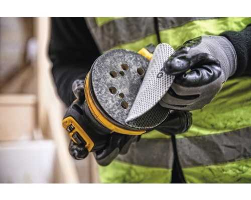 Muž mení brúsny papier na excentrickej brúske.