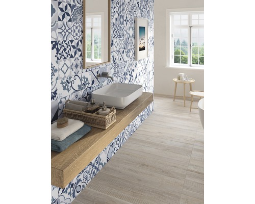 Svetlá kúpeľňa s umývadlom, zrkadlom, oknom a modro-bielymi vzorovanými obkladmi